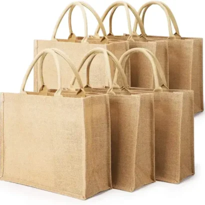 A group of durable, eco-friendly jute bags with sturdy beige handles, featuring a natural, textured finish. These reusable bags are rectangular in shape and ideal for shopping, gifting, or carrying everyday essentials