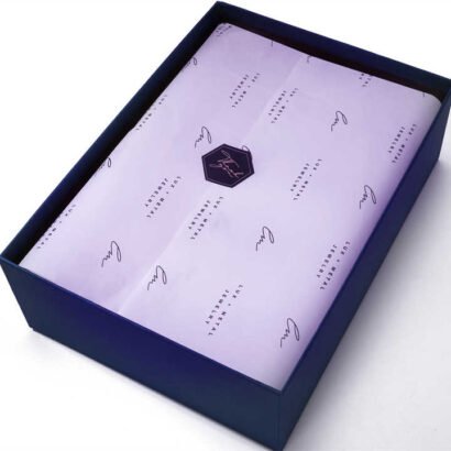 A box lined with personalized tissue paper featuring a custom logo and stylish design, perfect for elegant packaging and product presentation.