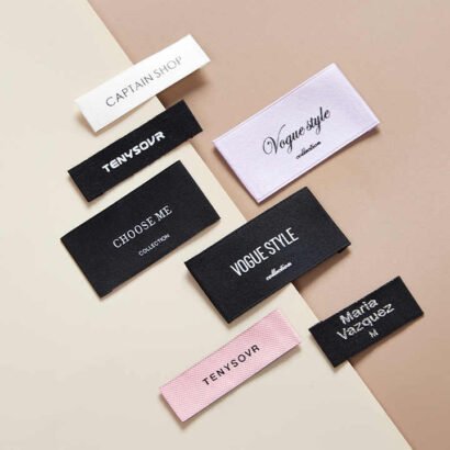 A selection of custom pure cotton labels in various colors and designs, ideal for branding on clothing, accessories, and handmade products.