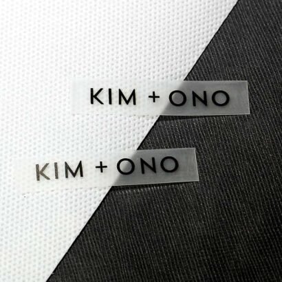 Two custom transparent rubber labels featuring the text "KIM + ONO," ideal for durable branding on garments, bags, and accessories.