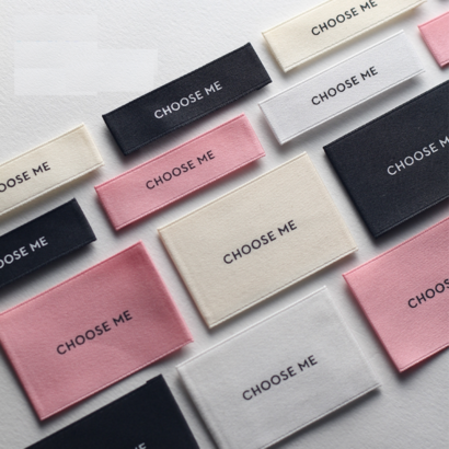 A set of custom fabric labels in various colors, featuring minimalist text "CHOOSE ME," ideal for branding apparel and accessories.